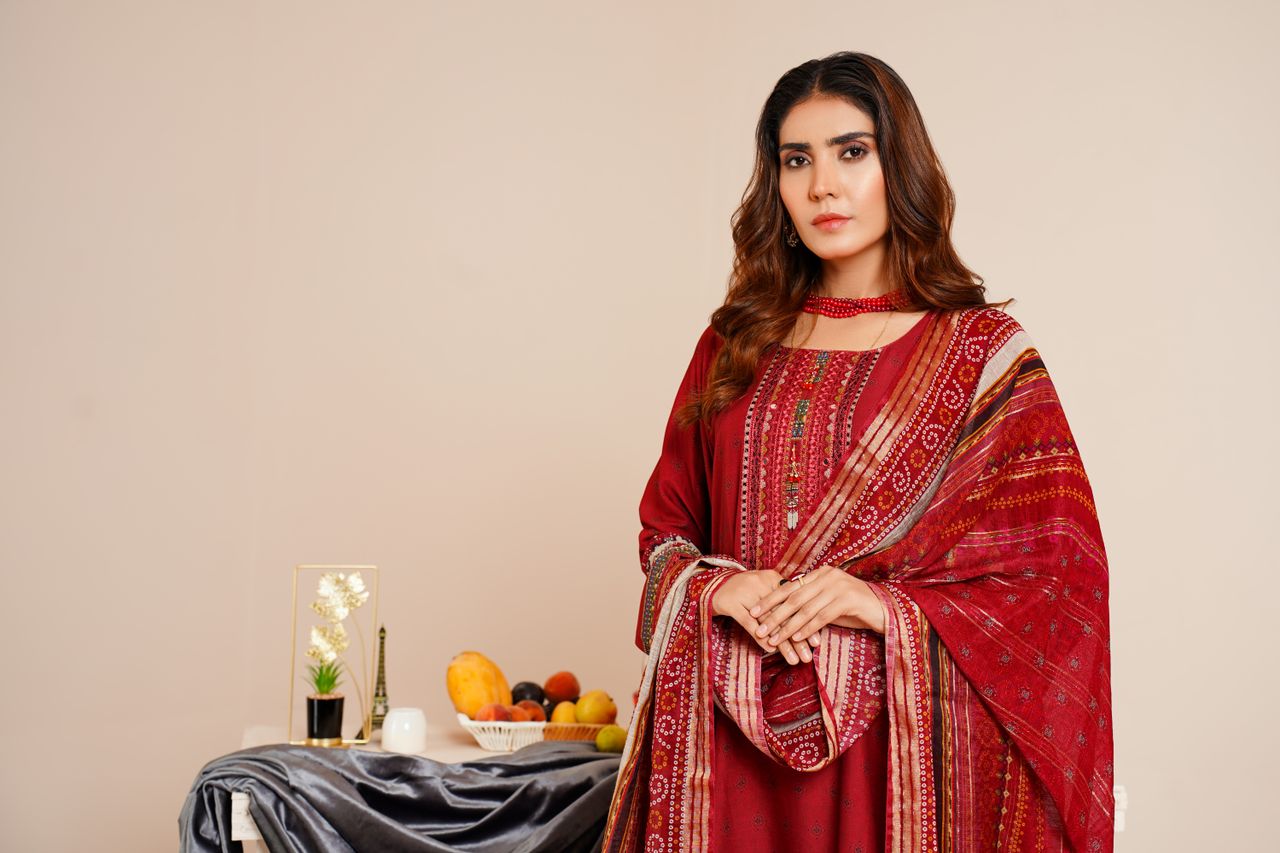 About South Asian woman in red traditional garment, standing indoors, fashion photography.